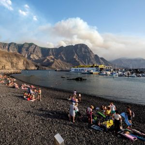 Personer på en strand på Gran Canaria betraktar röken från markbränderna.