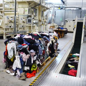 En stor hög med gamla kläder vid en produktionsanläggning som återvinner gamla textilier.