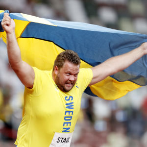 Daniel Ståhl rusar i väg med Sveriges flaggar unt axlarna.