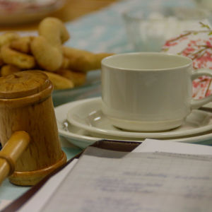 Kahvikuppi ja karjalaisia rotinaleivonnaisia kokouspöydällä, jossa myös puheenjohtajan nuija.