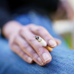 A woman's hand holding a burning cigarette.