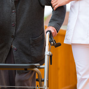 Person med rollator och person som tillhör sjukvårdspersonalen. 
