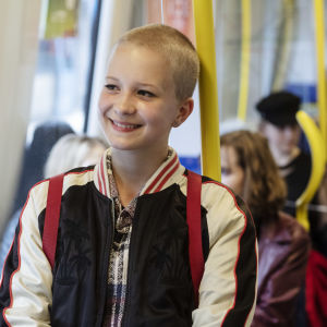Ung snaggad tjej som åker tunnelbana och ler.