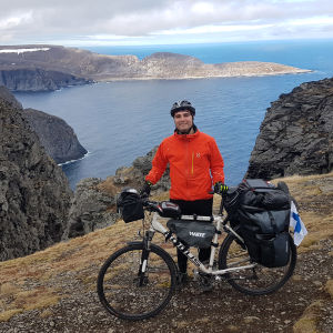 Teemu Hartman seisoo pyöränsä vieressä Norjassa kallioisella rannalla.
