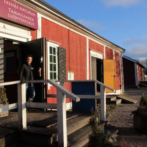 Kvinna öppnar dörren till ett hus.