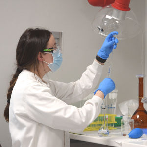 En kvinnlig kemist håller upp instrument i AstraZenecas laboratorium i Sydney där man jobbar med att ta fram ett coronavaccin.
