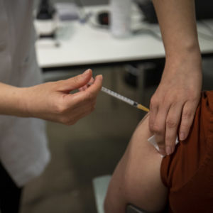 En skötare ger vaccin till en sittande person.