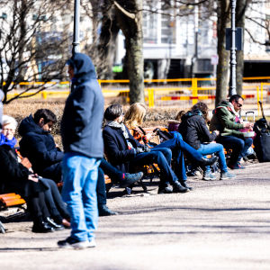 Ihmisiä istumassa Esplanadin puistossa aurinkoisena päivänä.