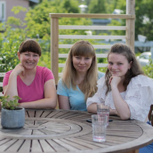 Minna Levälahti och de tre ukrainska kvinnorna som bor hos henne sitter runt ett bord på en terass.