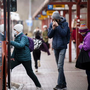 En person med munskydd stiger på en buss i Helsingfors.