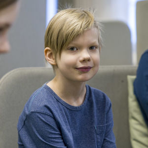 Lauritsalan koulun 3.-luokkalainen Aleksi Liutu istuu koulun oleskelutilassa ja katsoo kameraan. 