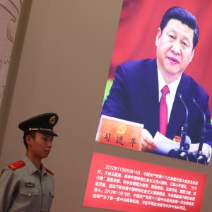 En polis står vakt vid en affisch med presiden Xi Jinping