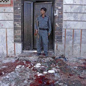 En afghansk polis intill attentatsplatsen i Kabul, där minst 31 människor dödades i ett självmordsattentat på söndagen. 