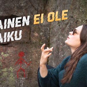 Teoskuvassa Salla Hämäläinen näyttää räppitunnusta sormillaan muinaisten kalliomaalausten edessä