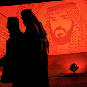 Saudier promenerar under ett porträtt av Prins Mohammad bin Salman