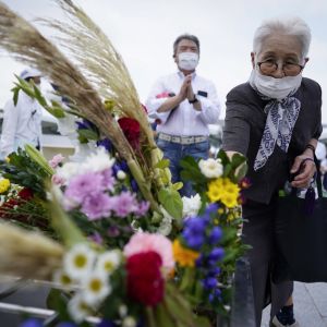 En äldre kvinna lägger blomma för att hedra de 210 000 dödsoffren i Hiroshima och Nagasaki.