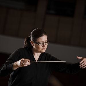 En kvinna i svart som dirigerar.