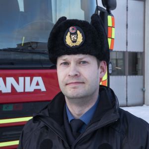Riskienhallintapäällikkö seisoo paloauton vierellä Neulamäen palolaitoksen pihalla.