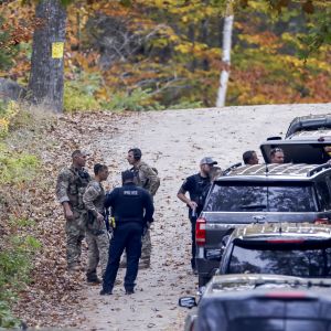 Tungt utrustade poliser och en rad med bilar i en skog i USA.