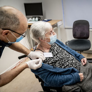 I Danmark har alla boende på servicehem redan hunnit vaccineras. Jytte Margrete Frederiksen får coronavaccin, Danmarks statsminister Mette Frederiksen följer med via videolänk.
