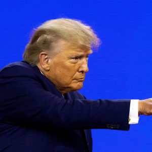 Donald Trump puvussa osoittaa jotakin sormellaan.