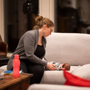 Kvinna pysslar om liten baby på soffa.