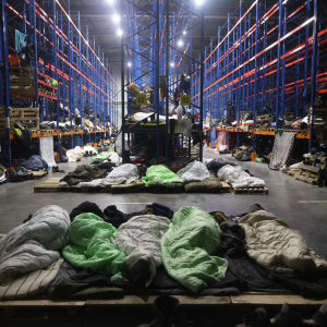 Migranter sover på rad i en lagerlokal.