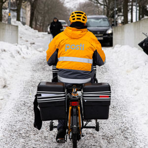 Postiljon cyklar på en vintrig lättrafikled.