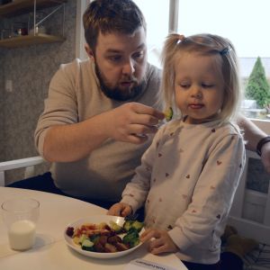 Christoffer Vidjeskog försöker mata dottern Lotta med broccoli men Lotta ser skeptisk ut.