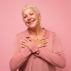 Leende äldre kvinna framför rosa bakgrund