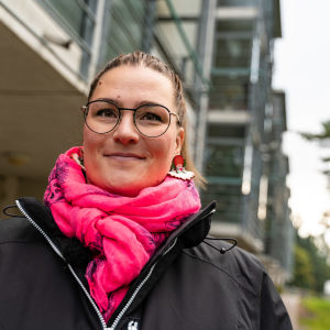 Mira-Veera Auer är ordförande för Gårdsbackas invånarkommitté. En kvinna står utanför ett höghus. Hon ler och ser in i kameran.