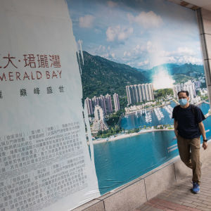 Mannen till höger passerar en reklamaffisch i bakgrunden av ett byggprojekt med höghus.