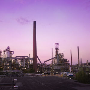 Ett oljeraffinaderi fotograferat i soluppgång, himlen är svagt lila.