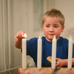 Pojke tänder det första ljuset i adventstaken.