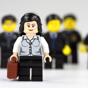 En affärskvinna som står framför en massa män iklädda kostym.