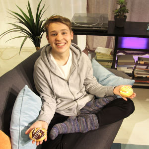 Jakob Norrgård sitter i en soffa med en bulle i varsin hand.