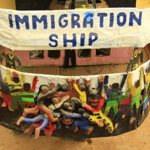 Bak på Immigration Ship kämpar immigranterna om att få komma ombord. Bak på the Immigration Ship hänger Afrianska flyktingar