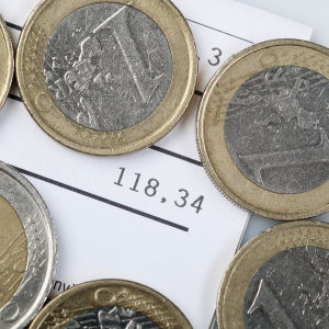 En hög med mynt ovanpå en räkning på 118 euro.