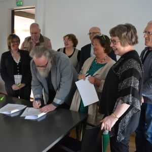 Flera personer samlade för att skriva under ett papper.