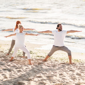 Grupp som yogar i vita kläder på en strand