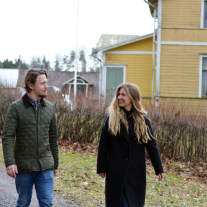 Oscar Gräsbeck och Ida Söderström går utanför ett stort gult trähus.