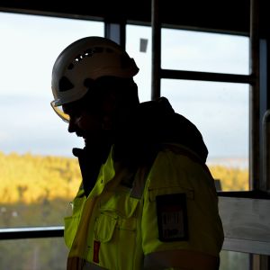 Siluetten av processkötare Ronnie Gustafsson inne på nyaste fabriken på Fermions fabriksområde i Hangö. I bakgrunden utsikt över skog. 