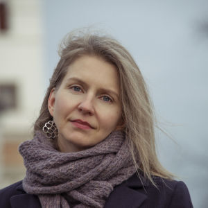 Filosofen Nora Hämäläinen har skrivit en bok om Trump och postmodernismen. Nora Hämäläinen fotgraferad utanför tornbyggnad, vind i håret, stor grå halsduk.