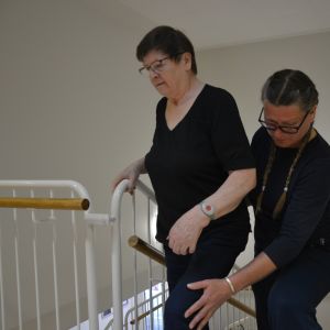 Pirkko Paananen övar sig på att gå i trappan, fysioterapeut Susanne Miikki stöder.
