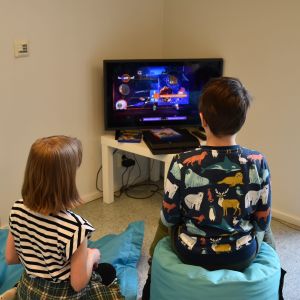Två barn spelar tv-spel och har ryggarna svängda mot kameran.