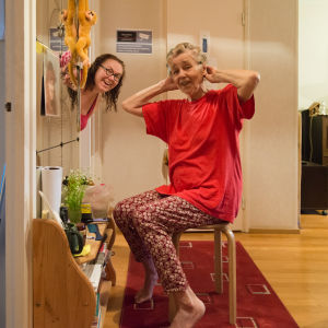 tytär kurkistaa ovesta, äiti etualalla laittaa papiljotteja
