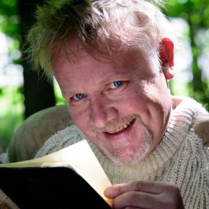Sagofarbrorn Mårten Holm läser en bok i skogen.