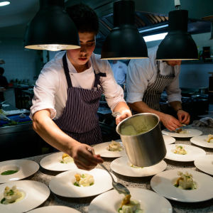 En kock sätter ut gourmetmat på tallrikar i en restaurang.