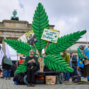 Människor demonstrerar i Berlin vid ett monument med skyltar med stöd för cannabis.