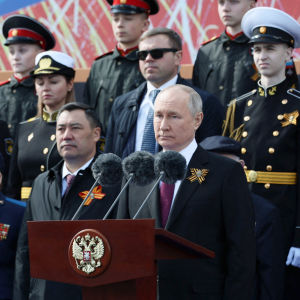 Vladimir Putin seisoo mikkirivin edessä, taustalla seisoo sotilaita ja veteraaneja rivissä.